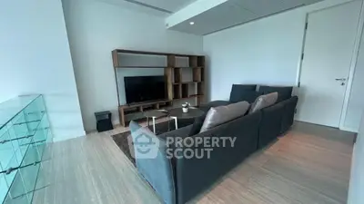 Spacious modern living room with elegant grey sofa, sleek wooden flooring, and a sophisticated entertainment unit, perfect for urban living.