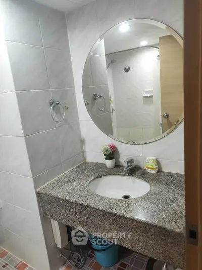 Modern bathroom with round mirror and granite countertop in stylish apartment.