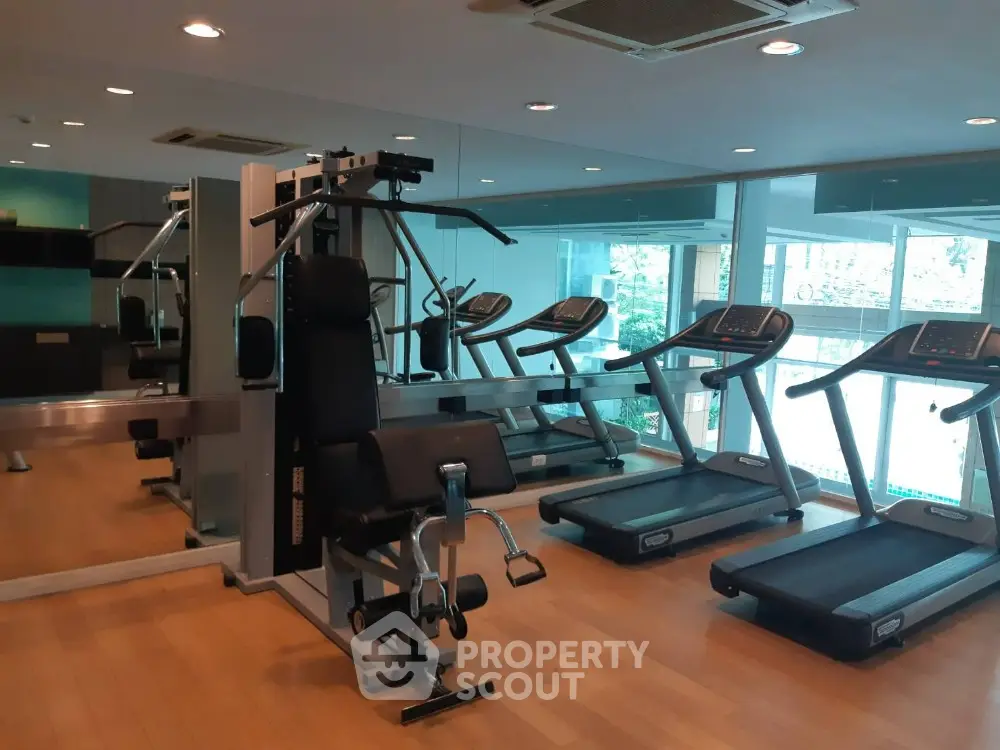 Modern gym with state-of-the-art equipment and mirrored walls in luxury apartment complex.
