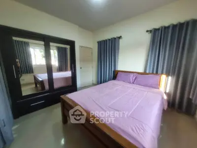Cozy bedroom with wooden bed and mirrored wardrobe, perfect for relaxation.