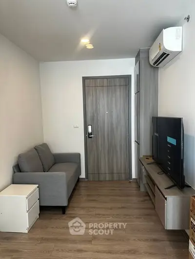 Modern living room with sleek furniture and wooden flooring, featuring a cozy sofa and flat-screen TV.