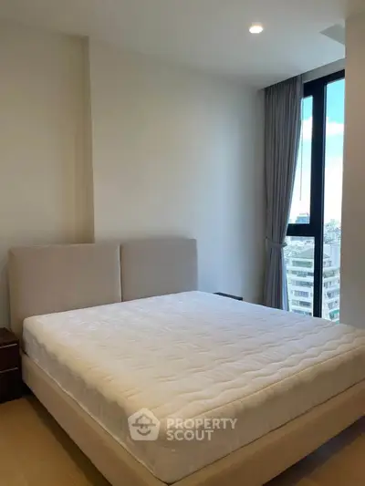 Modern bedroom with large window offering city view, featuring a comfortable bed and sleek design.