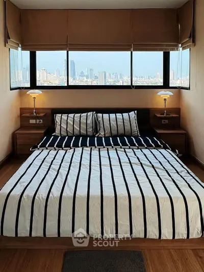 Luxurious bedroom with stunning city view and elegant striped bedding