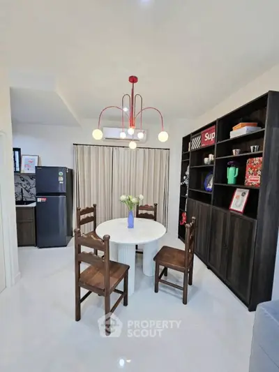 Charming dining area with modern lighting and stylish shelving in a cozy apartment.
