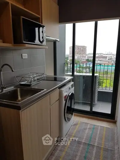 Modern kitchen with washing machine and balcony view in urban apartment