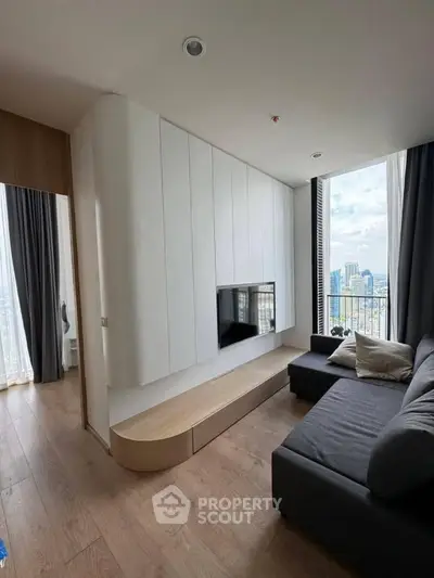 Modern living room with sleek design and city view, featuring a cozy gray sofa and built-in storage.