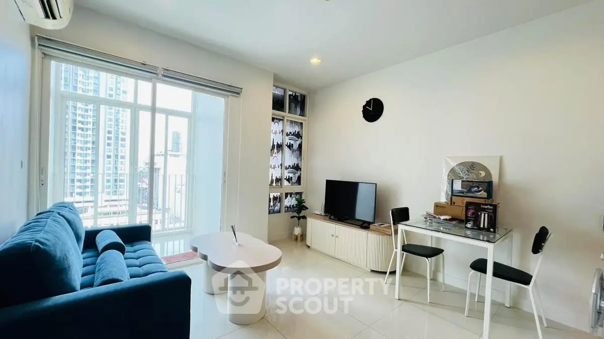 Modern living room with blue sofa, TV, and dining area in a high-rise apartment.