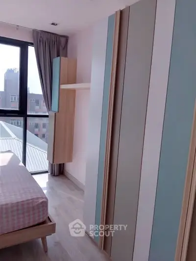 Bright bedroom with modern wardrobe and large window offering city view.