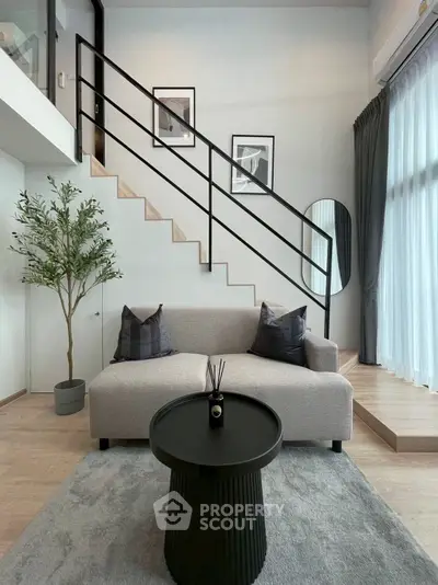 Modern living room with stylish staircase and cozy seating area in a bright, airy space.