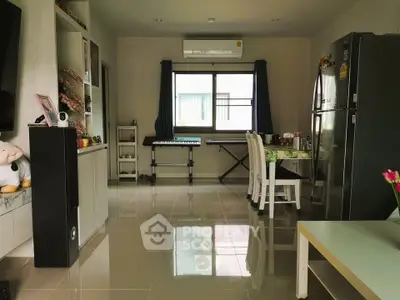 Spacious living room with modern decor and natural light, featuring a dining area and musical instruments.