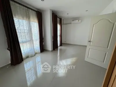 Spacious unfurnished room with large windows and elegant curtains