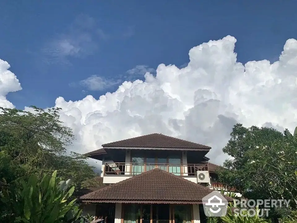 Stunning tropical villa with lush greenery and dramatic cloudscape