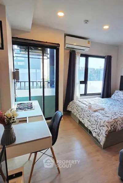 Modern bedroom with balcony view, stylish decor, and natural light in urban apartment.