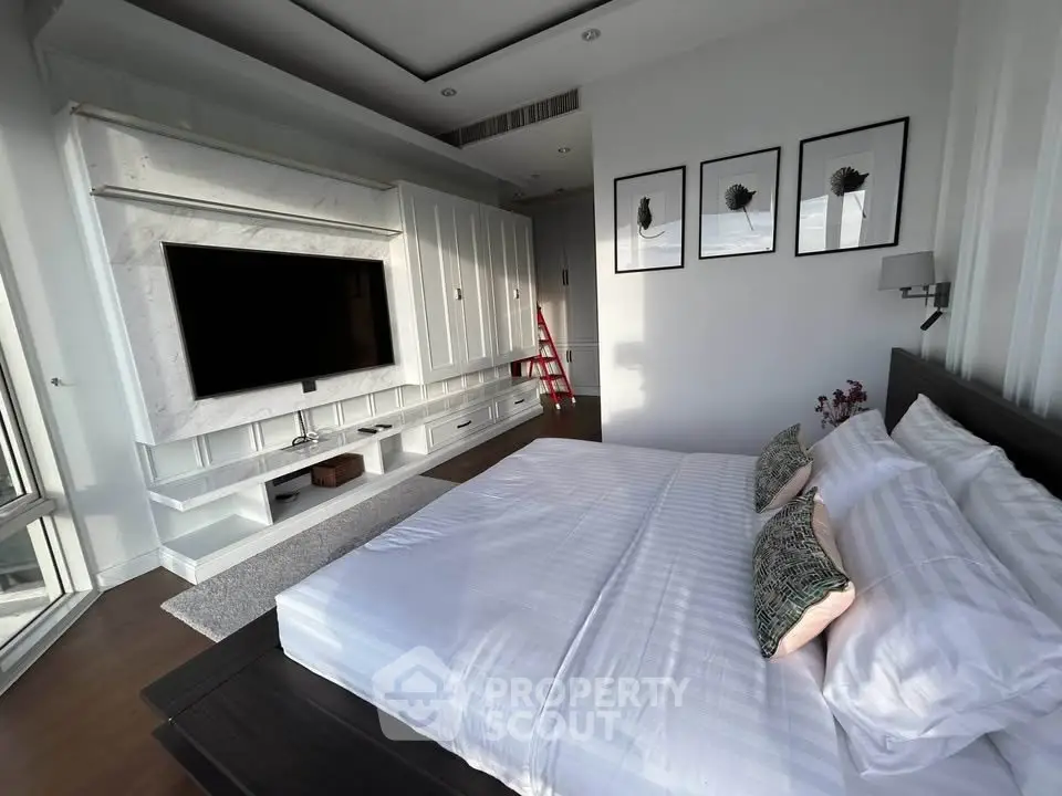 Luxurious bedroom with modern decor and large TV, perfect for relaxation and comfort.