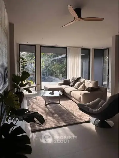 Spacious living room with modern furniture and large windows overlooking a lush garden.