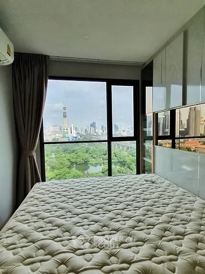 Modern bedroom with stunning city view from large window, featuring elegant decor and natural light.