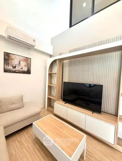 Modern living room with stylish furniture and wall-mounted TV, featuring a cozy beige sofa and wooden accents.