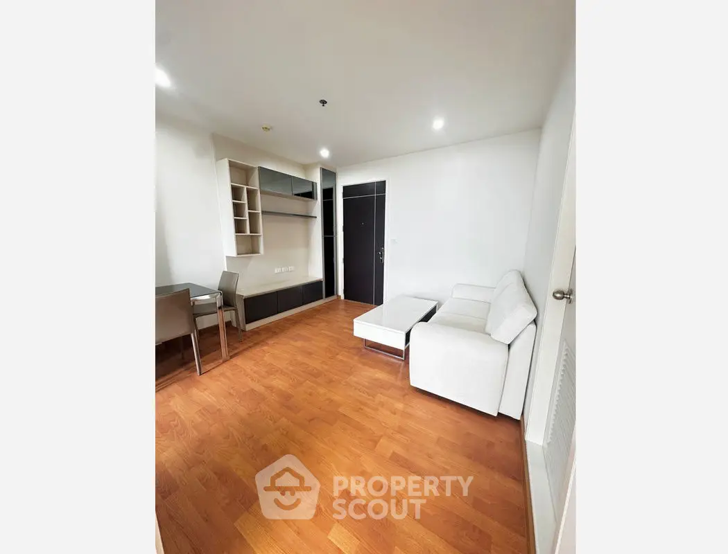 Modern living room with wooden flooring and sleek furniture in a cozy apartment.