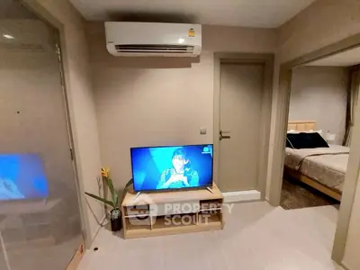 Cozy apartment interior with modern TV setup and air conditioning, leading to a stylish bedroom.