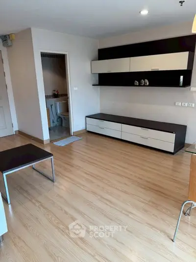 Modern living room with sleek wooden flooring and stylish storage units.