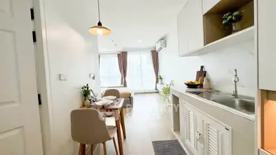 Modern open-layout apartment with stylish kitchen and cozy dining area, featuring large windows for natural light.