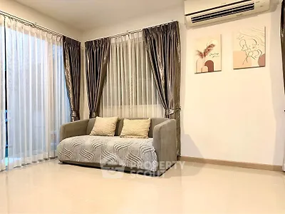 Elegant living room with modern sofa and stylish curtains, featuring wall art and air conditioning.