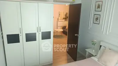 Cozy bedroom with white wardrobe and open door to living area