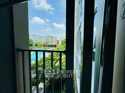 Stunning view from balcony overlooking lush garden and modern apartment complex.