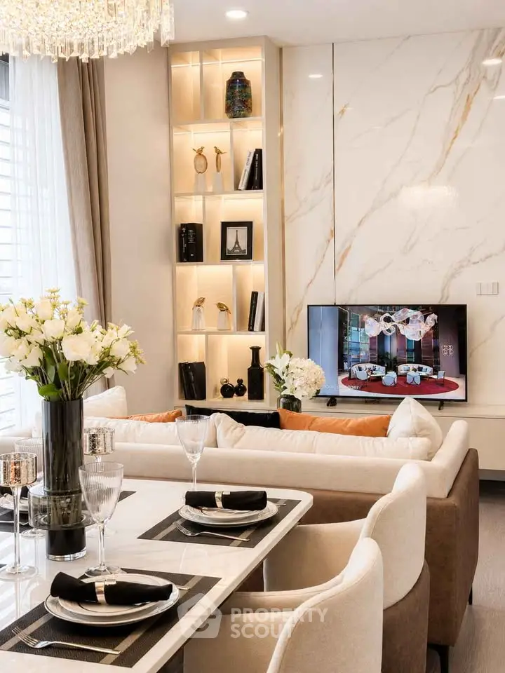Luxurious modern living room with elegant decor and open dining area, featuring a stylish TV setup and chic lighting.