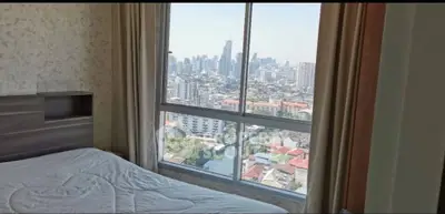 Stunning bedroom with panoramic city view from high-rise apartment window.