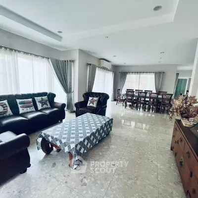 Spacious living room with elegant furniture and dining area, featuring large windows and stylish decor.