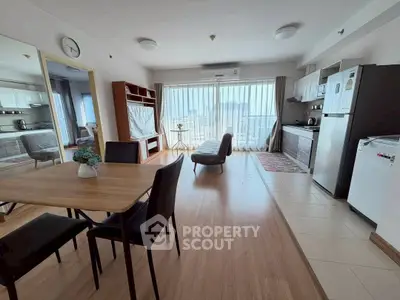 Spacious open-plan living room with modern kitchen and dining area, featuring large windows and stylish decor.