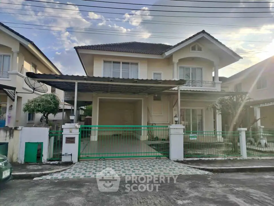 Charming two-story house with covered parking and green gate in a serene neighborhood.