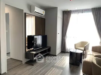 Modern living room with sleek furniture and large window, featuring a wall-mounted TV and air conditioning.