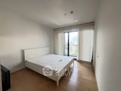 Spacious bedroom with large window and city view, featuring a minimalist design and wooden flooring.
