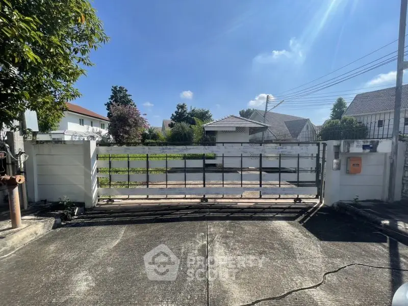 Spacious residential driveway with secure gate and lush greenery