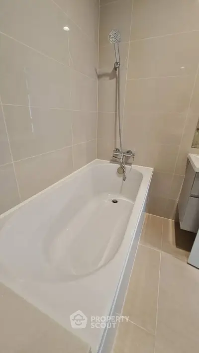 Modern bathroom with sleek bathtub and neutral tiles, perfect for relaxation.