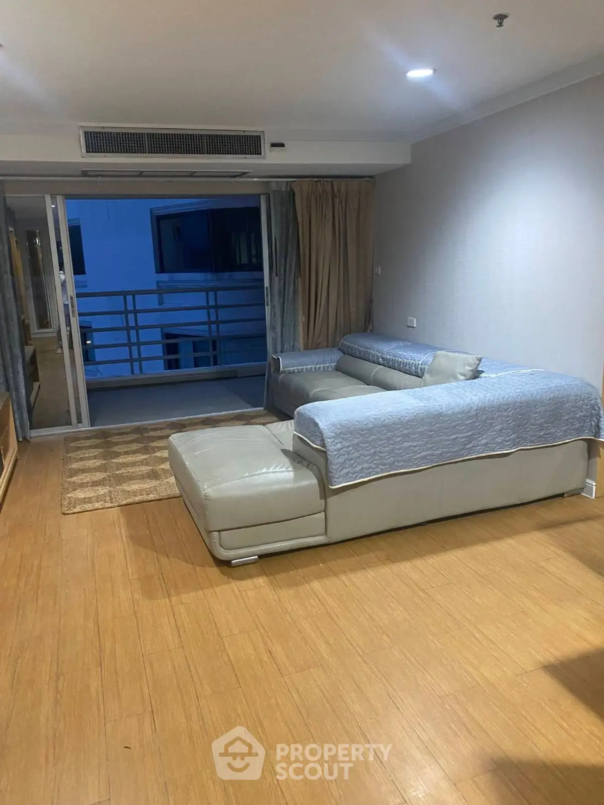 Spacious living room with modern sofa and balcony access in urban apartment.