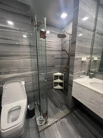 Luxurious modern bathroom with sleek gray marble tiles and glass shower enclosure.
