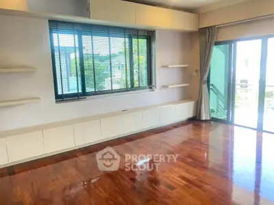 Spacious living room with wooden flooring and large windows offering natural light.