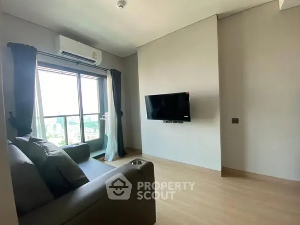Modern living room with sleek sofa and wall-mounted TV, featuring large window with city view.