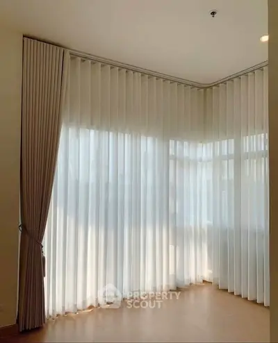 Spacious corner unit with elegant floor-to-ceiling windows and sheer curtains, perfect for natural light.