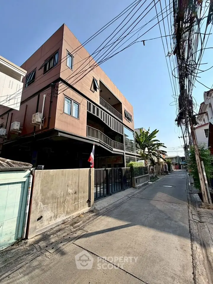 Modern multi-story building with unique architectural design on a quiet street, ideal for urban living.