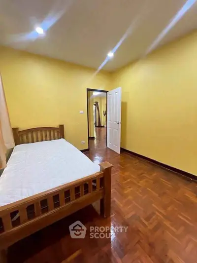 Spacious bedroom with wooden flooring and cozy bed in a well-lit interior.