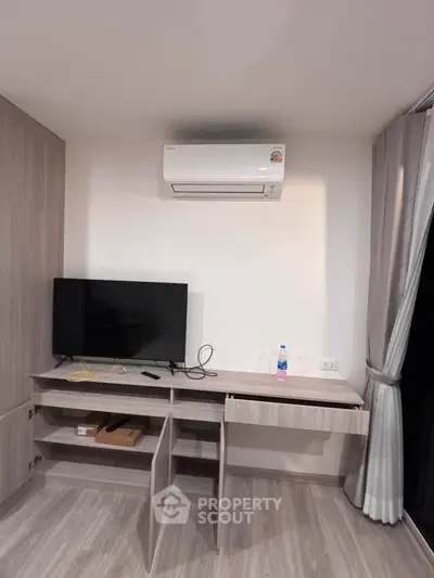 Modern study area with desk, TV, and air conditioning in a stylish apartment.