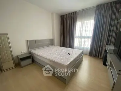 Spacious bedroom with modern decor and large window for natural light.