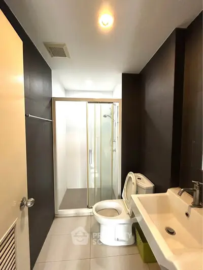 Modern bathroom with sleek design, featuring a glass shower enclosure and contemporary fixtures.