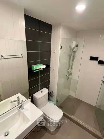 Modern bathroom with sleek design, featuring a glass shower enclosure and contemporary fixtures.