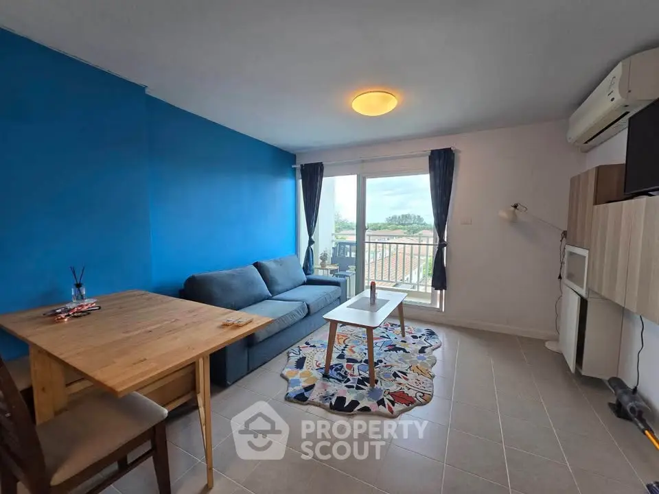 Modern living room with blue accent wall, cozy sofa, and balcony view.