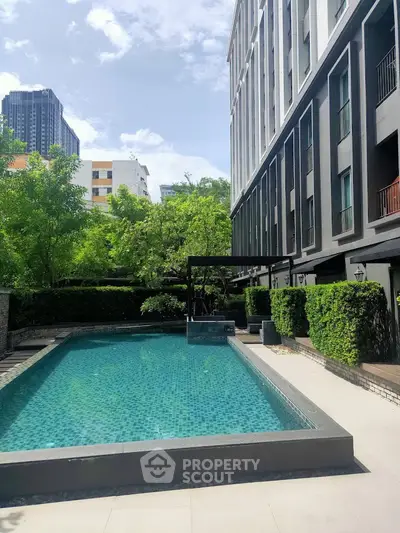 Luxurious modern apartment building with a pristine outdoor pool and lush greenery, perfect for relaxation.